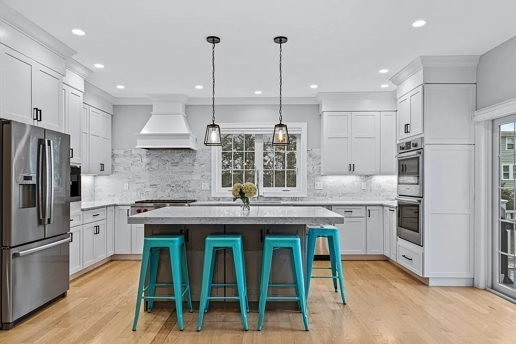 WHite shaker kitchen cabinets with island and whote countertops and built in coffee machine