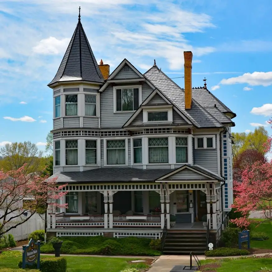 Victorian home with a turret on the left and farmers porch. It is 2.5 stories high