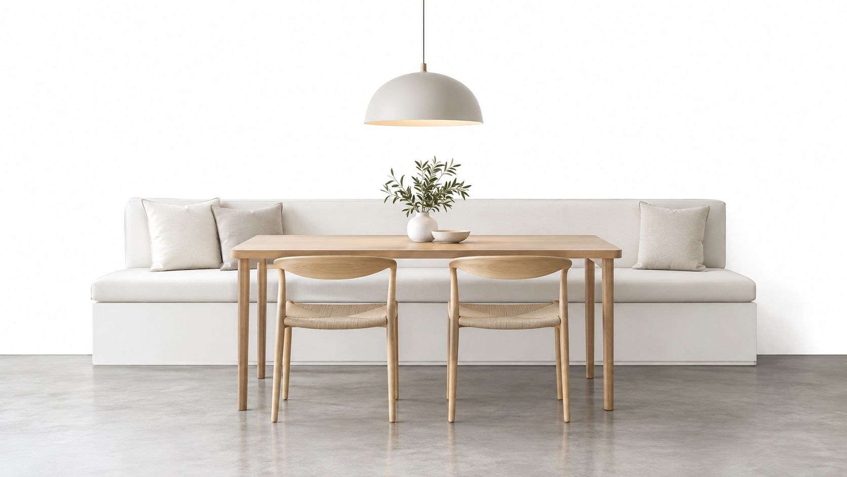 A modern minimalist dining room featuring a wooden table, woven chairs, and a comfortable white bench seat.