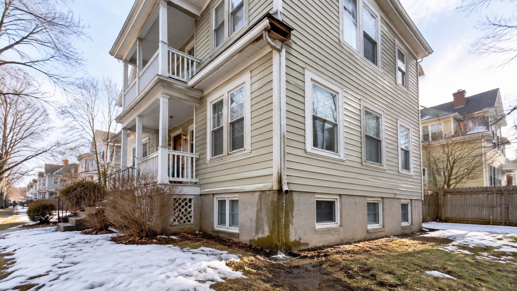 A house exterior showing improper downspout drainage causing water runoff against the foundation of the home.