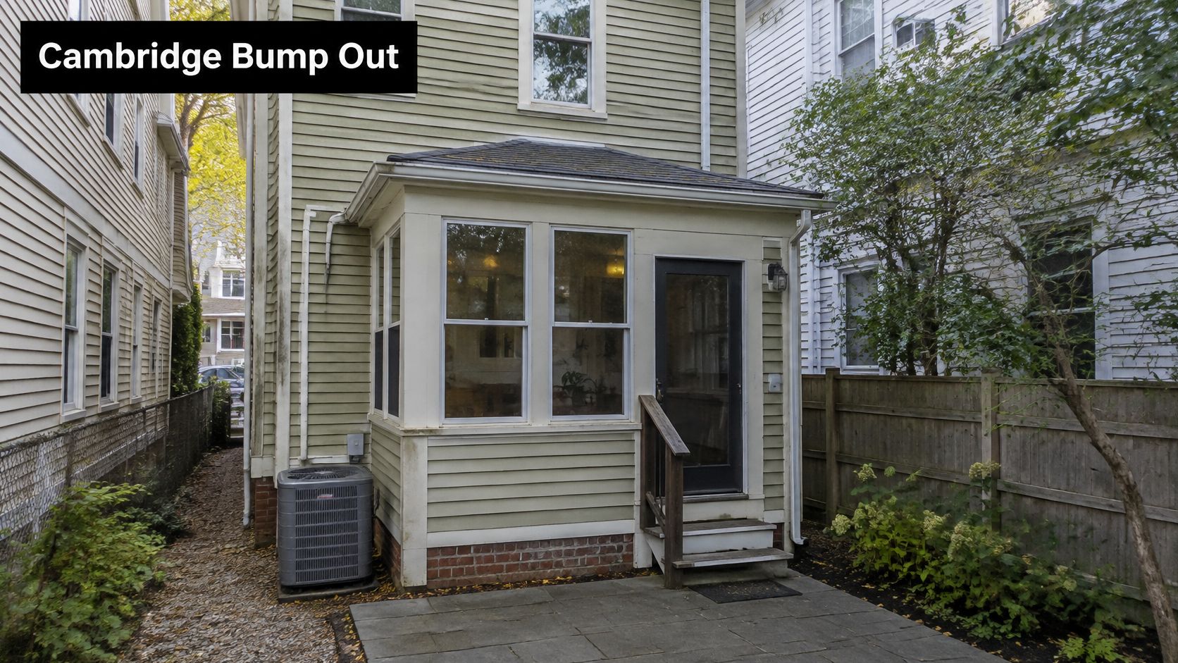 The exterior of a residential home addition featuring a light green bump out with windows and a door.
